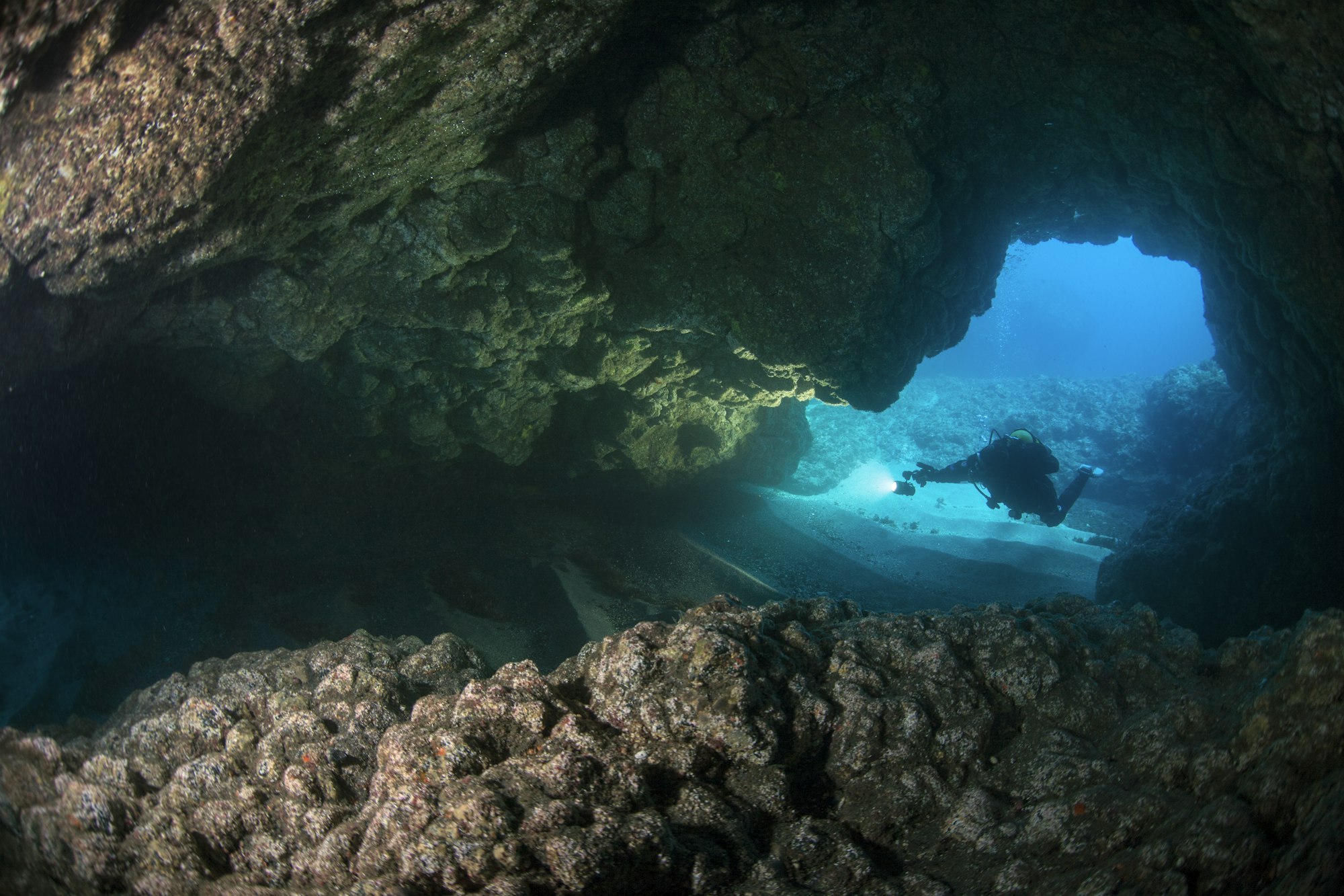 Silhouetted Scuba Diver Enters an Underwater Cavern